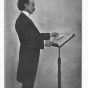 Black and white photograph of Oberhoffer at behind a podium, c.1903. 