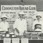 Black and white photograph of three girls in the Crookston Bread Club display baked goods and the recipes used to make them, 1920.