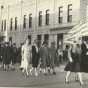 Black and white photograph of Members of Crookston’s BPW club walking with the American flag down Main Street in a parade, ca. 1940s.