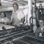 Black and white photograph of staff of the Waconia Patriot at a printing press. Art Wessele is shown in the middle. Date and photographer unknown.