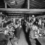 Black and white photograph of Lumberjacks eating in lumber camp dining hall, ca. 1916. 