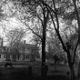 Black and white photograph of Harrington-Merrill house with Harry Merrill standing in the foreground, 1890.