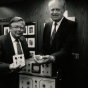 Black and white photograph of Medtronic Founder Earl Bakken and Medtronic CEO Winston Wallin with an early pacemaker model, 1986. Photographed by Jeffrey Grosscup.  