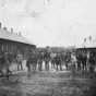 Black and white photograph of some members of the First Minnesota Mounted Rangers in front of temporary barracks outside the walls of Fort Snelling, 1864.