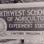 Black and white photograph of the entrance sign for the Northwest School of Agriculture and Northwest Experiment Station.  