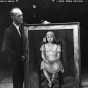 Black and white photograph of Knute Heldner holding a painting created by Elsa Jemne for the WPA Federal Art Project and exhibited at the Minnesota State Fair, c.1936.