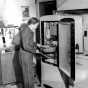 Black and white photograph of Linda Benitt at the refrigerator in her kitchen, Dakota County, 1944.