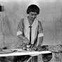 Black and white photograph of a woman on a farm ironing, ca. 1925.