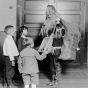 Black and white photograph of a worker dressed as Santa, passing out gifts at the Neighborhood House, c.1925. 