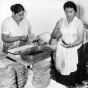 Black and white photograph of Mrs. Julio Lopez and Mrs. Francisco Rangle prepare food for an Mexican Independence celebration, Our Lady of Guadaloupe Church, September 15, 1958.