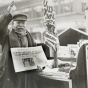 Black and white photograph of a man selling a newspaper with headline related to Bremer kidnapping, 1935. 