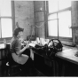 Black and white photograph of an employee knitting a sock to cover an amputated limb, Winkley Artificial Limb Company, Minneapolis, 1937. 