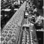 Black and white photograph of Honeywell Round thermostats ready for final checkout and packaging at a factory in Golden Valley, c.1955. 