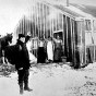 Photograph of men waving to Frank Higgins, the lumberjack sky pilot, outside a lumber camp c.1910.