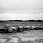 Black and white photograph of highway trucks delivering grasshopper poison to farmers, 1938. 