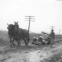 Horses pulling a car out of mud on a dirt road 