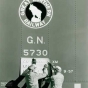 Black and white photograph of load capacity figures being stenciled on a Great Northern Railway boxcar, ca. 1957.