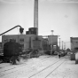 Black and white photograph of the Como Shops complex of the Northern Pacific Railway, located just south of Como Park in the St. Paul Midway, 1948. A railroad crane is parked next to the powerhouse building. 