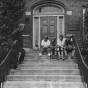 Black and white photograph of a boys wearing football helmets on the front steps of the Northeast Neighborhood House, 1927.