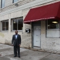 Color image of Wali Dirie, executive director of the Islamic Civic Society of America and Dar Al-Hijrah Mosque, stands outside their new entrance at 504 Cedar Avenue, 2015.