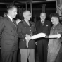 Black and white photograph of Major General Norman Kirk, Surgeon General of the Army, inspecting Minnesota-made artificial limbs, December 6, 1943.