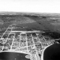 An aerial view of Grand Marais, ca. 1955. The diagonal white line that can be seen in the background is the Gunflint Trail.