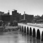 Black and white photograph of the Great Northern Railway’s Winnipeg Limited crossing the Stone Arch Bridge, Minneapolis, ca. 1955.