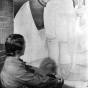 Black and white photograph of a mural in Minneapolis Armory by Elsa Jemne (seated before mural), c.1940. 