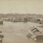 Black and white photograph looking north across the Flats during high water 1881. The raised street is Wabasha.