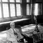 Black and white photograph of Sy Mergens relaxing in the Fireside Room of the University Club, June 22, 1977. Photographed by Julian G. Plante.