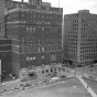 Black and white photograph of the St. Paul Athletic Club and surrounding buildings. View of the intersection of Fourth Street East and Cedar Avenue, St. Paul. The St. Paul Athletic Club is at center left.