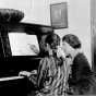 Black and white photograph of a girl being given piano lesson at the Northeast Neighborhood House, c.1925.