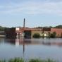 Color image of north and west façades of Faribault Woolen Mill with Cannon River in the foreground, 2011.