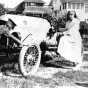 Black and white photograph of a Red Cross nurse, and likely Motor Corps officer, 1918. The car has the Red Cross symbol on the hood and was likely part of the Minnesota Motor Corps. 