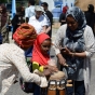 Photograph of a child playing a traditional Somali drum with help from adults