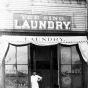 Yee Sing Woo standing in front of Yee Sing Laundry, 1319 Nicollet, Minneapolis