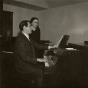 Black and white photograph of composer Paul Fetler (at the piano) with Alice Gustava Smith (Sister Maris Stella), c.1969.