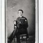 Photograph portrait of Martin Webb. He is seated in a chair with his legs crossed and he is wearing his uniform.