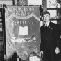 A black and white photograph showing CCHS President O.D. Sell in Mayer with a donated banner from the German Reading Society.