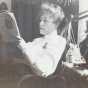 Black and white photograph of Eliza Childs reading a newspaper, ca. 1900–1910.