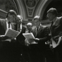 Black and white photograph of Ron Dicklich, William Luther, Allan Spear, Roger Moe, and Duane Benson reading a bill on the floor of the Minnesota Senate, 1988. 