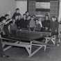 Black and white photograph of two boys playing ping pong at the Jewish Educational Center Annex while a group of children looks on, 1940.