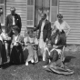 Black and white photograph of Sinclair Lewis and friends, ca. 1916. Lewis sits in the rocking chair at right; his wife, Grace Hegger Lewis, wears a maid’s uniform and stands at left.