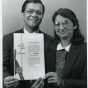 Black and white photograph of Sam (Smarajit) and Sumita Mitra, a husband-and-wife team of 3M research scientists, display their U.S. patent for copolymerizable UV stabilizers, 1987.
