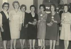 Black and white photograph of Mrs. Matzke, Miss Olson, and Miss Nelson present yellow carnations to initiates Luverne Sorenson, Deborah Hanson, Eloise Espe, and Clara Kelly at an initiation meeting for new BPWC members, 1966.