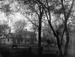 Black and white photograph of Harrington-Merrill house with Harry Merrill standing in the foreground, 1890.