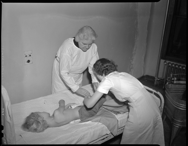 Sister Elizabeth Kenny examining a child and lecturing to visitors.