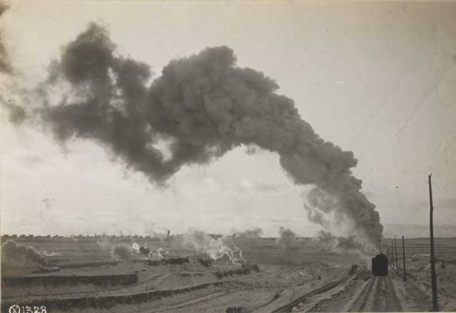 An Oliver Mining Company locomotive hauls ore away from an open pit near Hibbing, Minnesota, 1917. The young city is visible in the background.