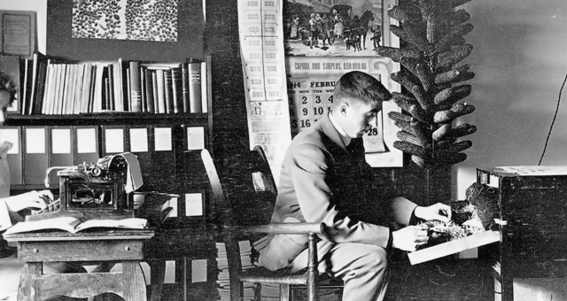 Black and white photograph of Alfred Carlsted counting sprouted kernels to determine the percent that germinated, 1914.