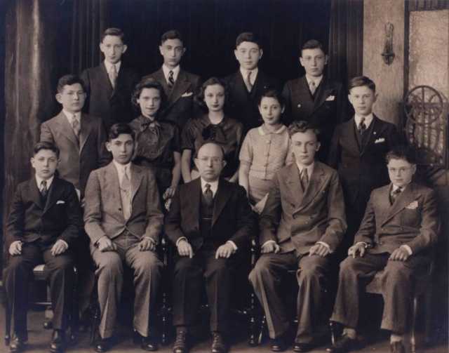 Black and white photograph of young men and women of the 1935 graduating class of the St. Paul Talmud Torah. Max Gordon, the director of the Talmud Torah, is seated at the center of the front row.